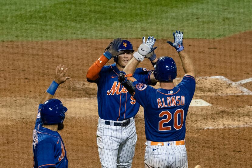 El jugador de los Mets Luis Guillorme (izquierda), celebra con sus compañeros Brandon Nimmo (9) y Pete Alonso (20) luego de conectar un doble.