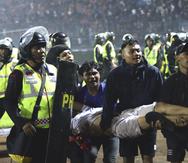 Un grupo de aficionados carga a un hombre herido en los enfrentamientos durante un partido de fútbol en Malang, Indonesia.