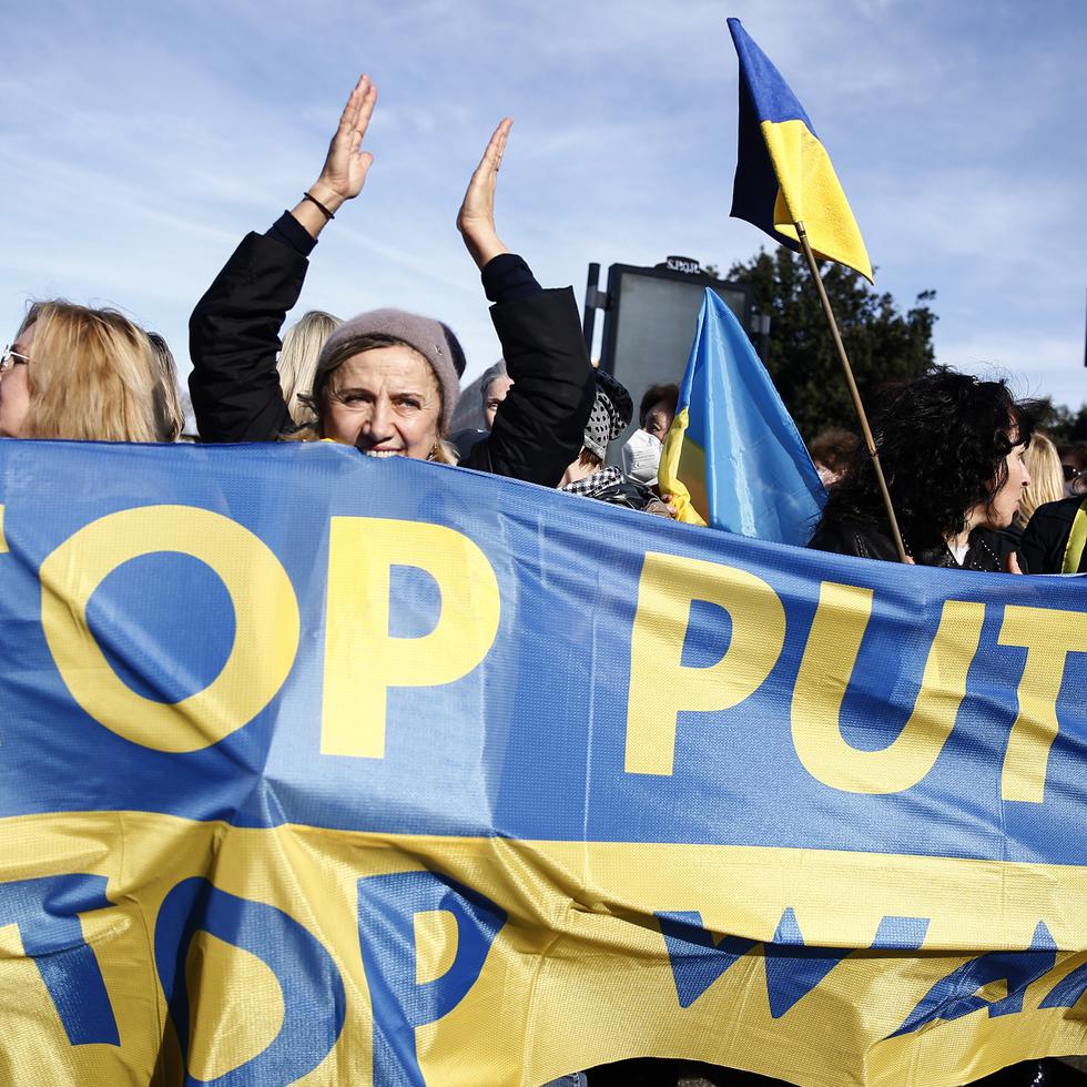 Manifestantes sostienen una pancarta con los colores nacionales de Ucrania y el mensaje "Detengan a Putin", cerca de la embajada rusa en Roma, el 24 de febrero de 2022.