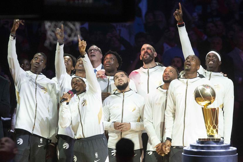 Los Raptors de Toronto, observan el despliegue del banderín conmemorativo del título que consiguieron la campaña anterior, el martes 22 de octubre de 2019, durante una ceremonia previa al encuentro inaugural de la nueva temporada. (AP)