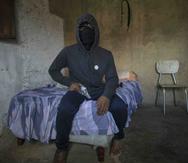 Un pandillero enmascarado apodado "El Negrito" posa para un retrato con su arma en una casa segura de su pandilla en la barriada de Petare, en Caracas, Venezuela, el lunes 13 de mayo de 2019. (AP/Rodrigo Abd)