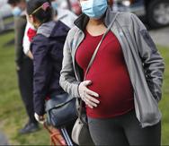 Una mujer embarazada aguarda en una fila en la iglesia de Santa María en Waltham, Massachusetts, para gente necesitada de comestibles debido a la pandemia de COVID-19.