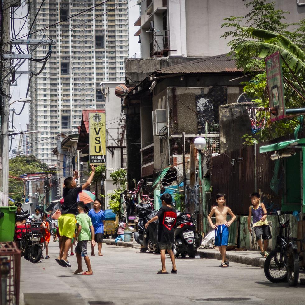 Unos jovencitos filipinos juegan baloncesto en una de las calles de la ciudad capital.