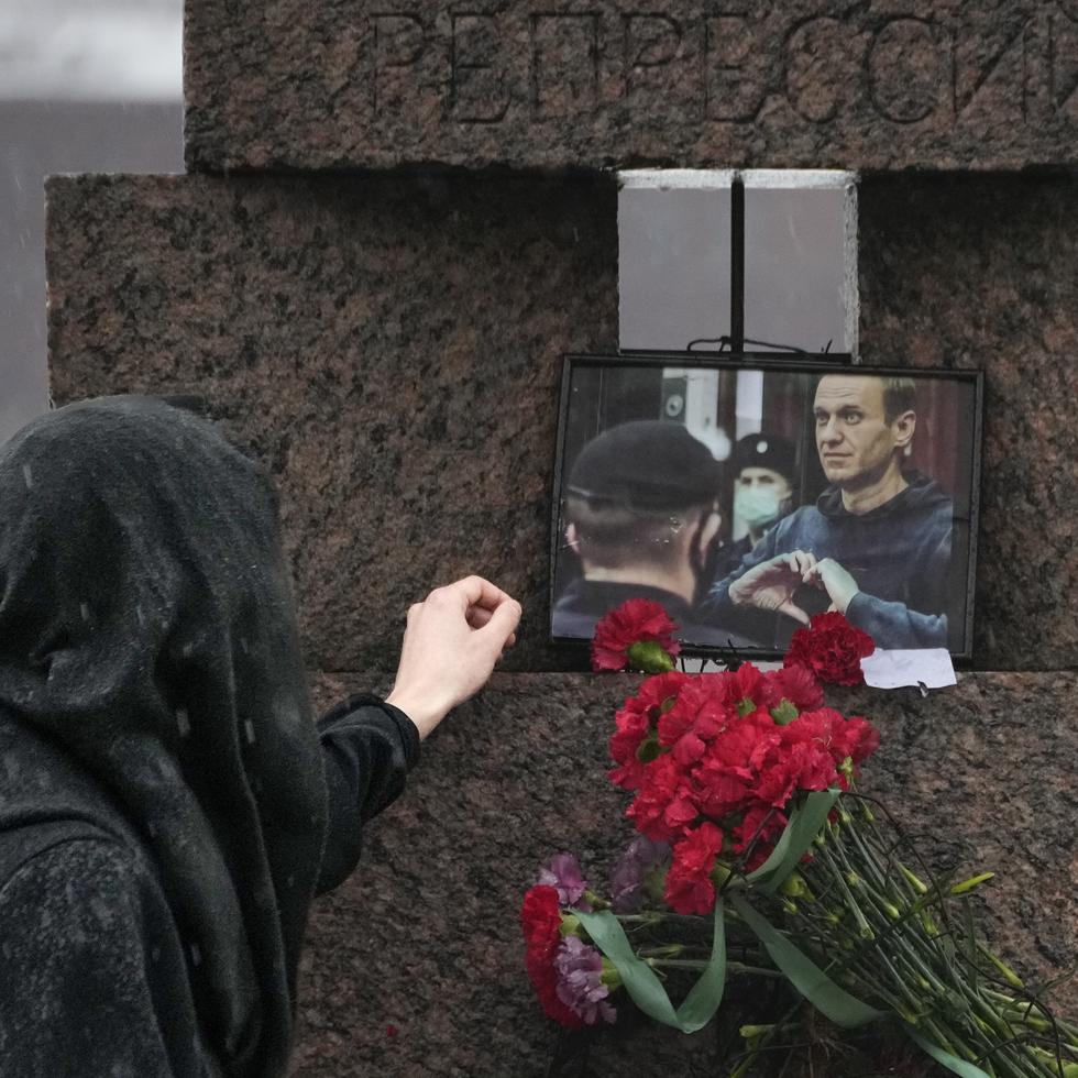 Una mujer toca la fotografía de Alexei Navalny tras dejar flores en homenaje al fallecido líder opositor ruso, en San Petersburgo, Rusia.
