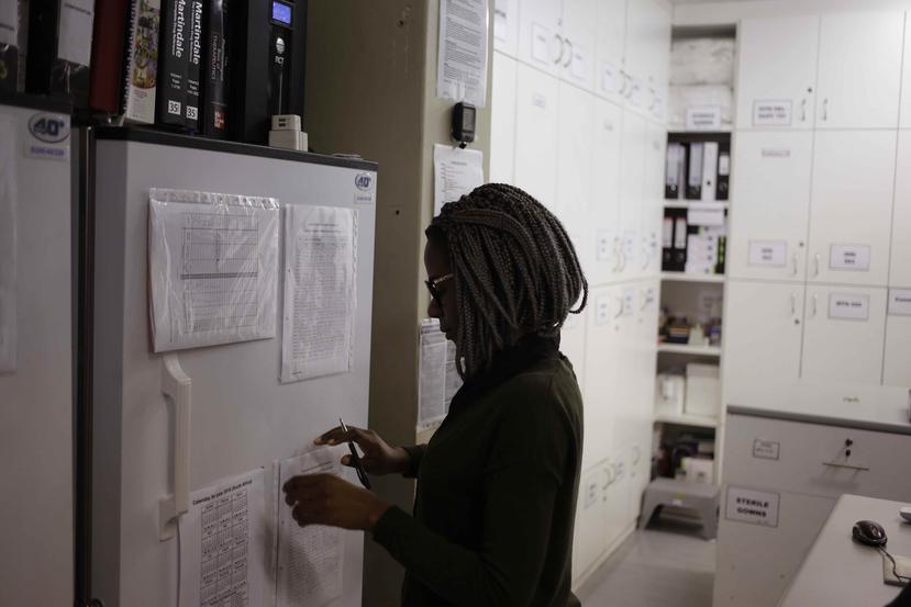 La farmacéutica Mary Chindanyika mira documentos en un refrigerador que contiene una vacuna de prueba contra el VIH en Sudáfrica. (AP)
