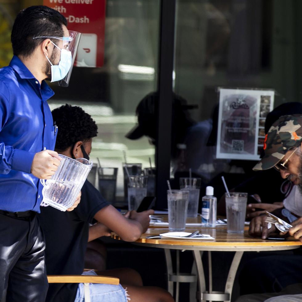 Un mesero usa una mascarilla mientras atiende a los comensales en un restaurante en California. /ArchivoEFE/EPA/ETIENNE LAURENT
