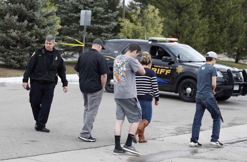 En la foto varios de los presentes en la escuela durante el incidente regresan a sus vehículos. (AP)