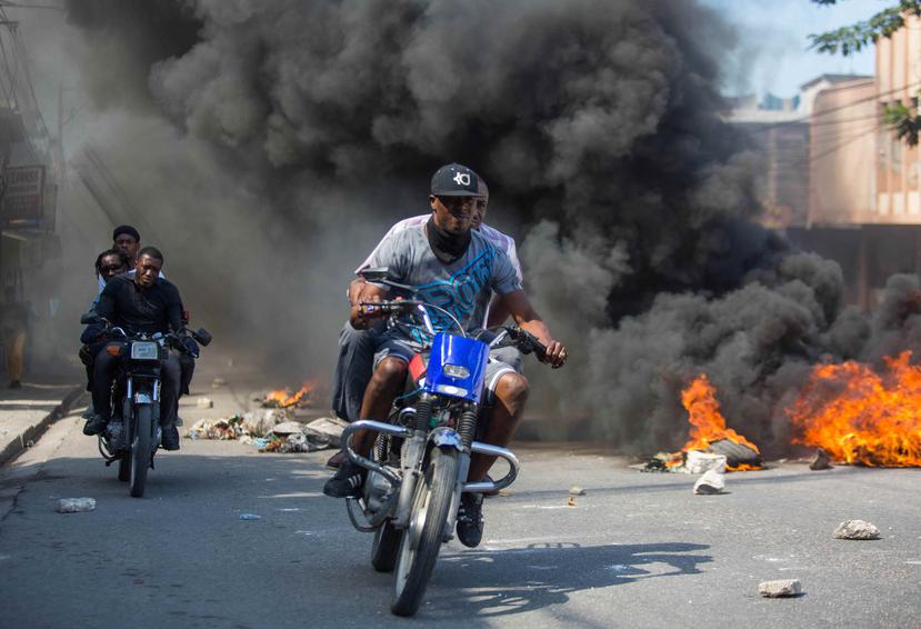 Manifestantes atraviesan en una motora varias barricadas durante una manifestación en Puerto Príncipe, Haití. (EFE)