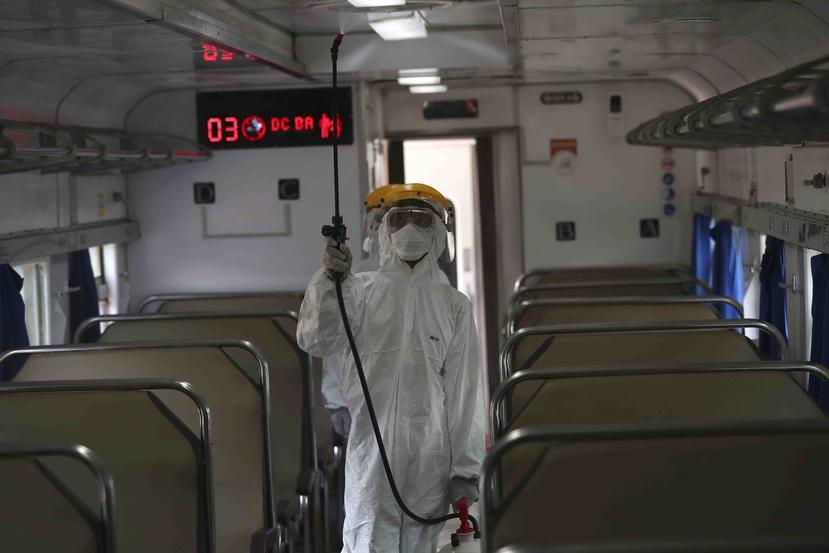 Un empleado con equipo de protección rocía desinfectante en un tren para combatir un brote de coronavirus en la estación de tren de Senen, en Yakarta, Indonesia. (AP)