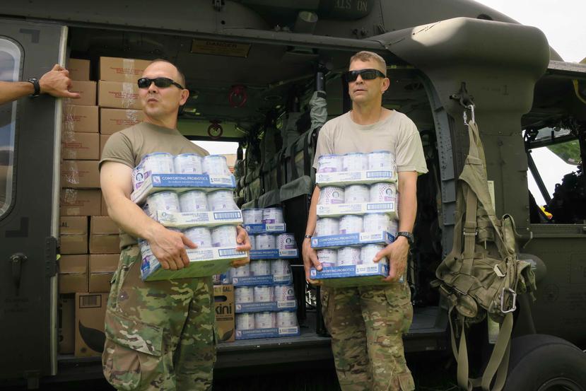 El general Jeffrey Buchanan (derecha) junto a otro militar cargan cajas de comida para bebés en una visita a Jayuya. (EFE / Jorge Muñiz)