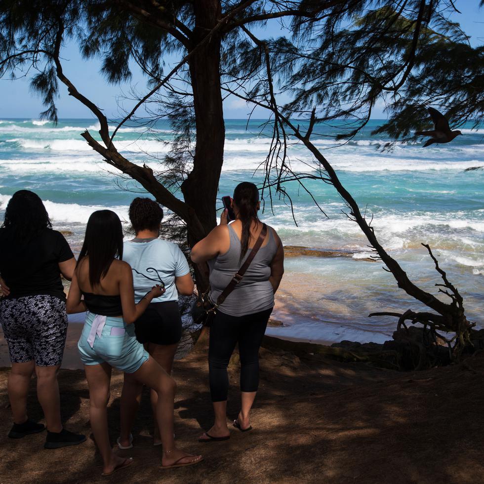 Personas observan el oleaje en una playa en Loíza.