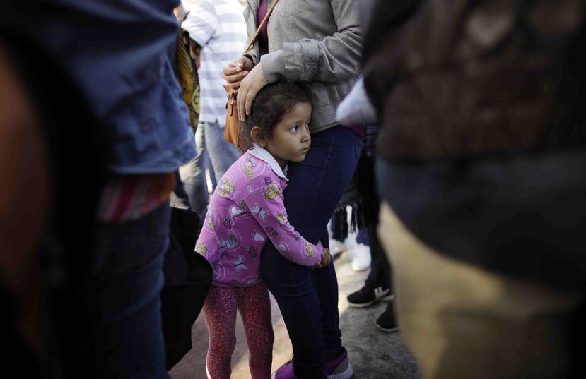 Nicole Hernández, de Guerrero en México, se aferra a las piernas de su mamá mientras aguardan para solicitar asilo político en la frontera en los Estados Unidos mediante el cruce fronterizo en Tijuana. (AP / Gregory Bull)