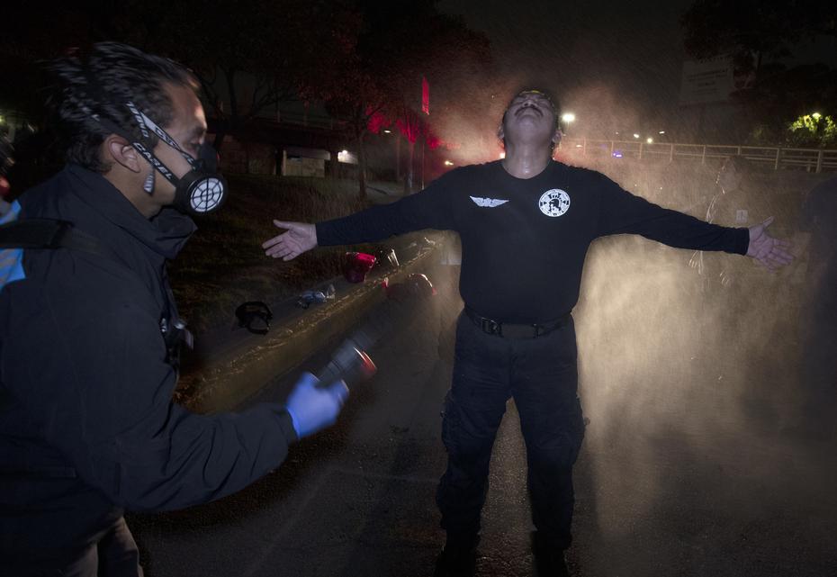 En esta imagen del 30 de mayo de 2020, Óscar Becerril, coordinador de paramédicos, desinfecta a su colega César Ávila después de salir a recoger a un paciente enfermo de COVID-19 desde su base en Iztapalapa, una demarcación de la Ciudad de México.