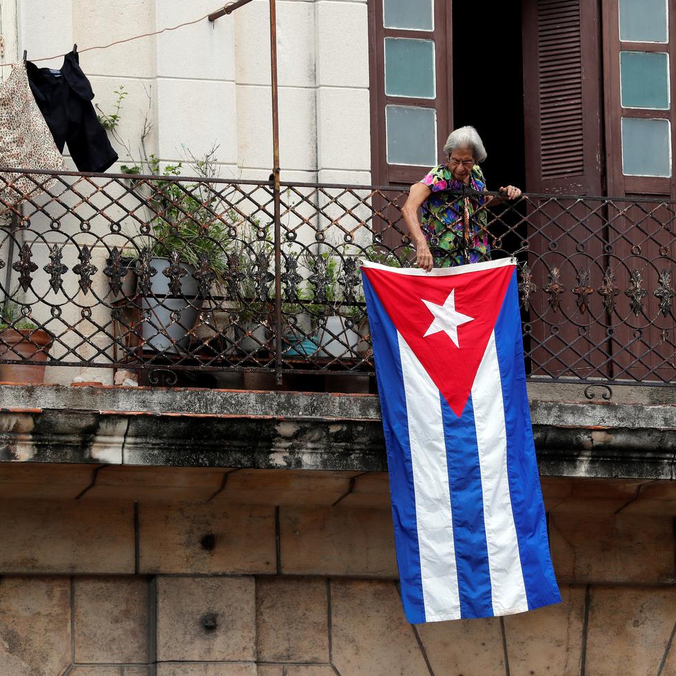 Una mujer sale al balcón donde se expone una bandera cubana, hoy en La Habana, Cuba. EFE/Ernesto Mastrascusa
