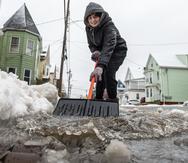 Amber Vallee pushes water down Walnut Street in Lewiston, Maine, Saturday morning, Jan 13, 2024, after snow turned to rain during yet another storm of mixed precipitation hit the area. "I wish it was all snow. I'm tired of this slush that will turn into ice at the bottom of our driveway." she said while keeping a path open for the rain and melting snow to flow into a nearby storm drain. (Russ Dillingham/Sun Journal via AP)