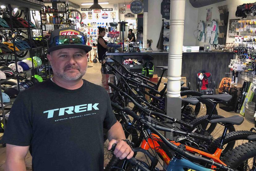 Brian Morris, propietario de Freeride Bike Company en Gilbert, Arizona, posa dentro de su tienda, que no ha frenado su actividad económica pese a la pandemia. (AP Foto/John Marshall)