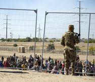 Imagen de archivo de gran cantidad de migrantes junto a la verja fronteriza para entrar en El Paso, Texas, ante la mirada de miembros de la Guardia Nacional del estado.