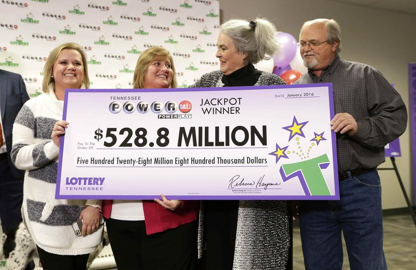 Rebecca Hargrove, 2da derecha, presidente de la lotería de Tennessee, entrega un cheque simbólico a John Robinson, derecha, su esposa Lisa y su hija Tiffany, después de cerrtificar su boleto ganador.
