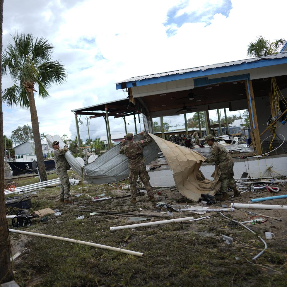 Miembros de la Guardia Nacional ayudan a un negocio afectado por el huracán Idalia a mover y apilar escombros, en Horseshoe Beach, Florida.