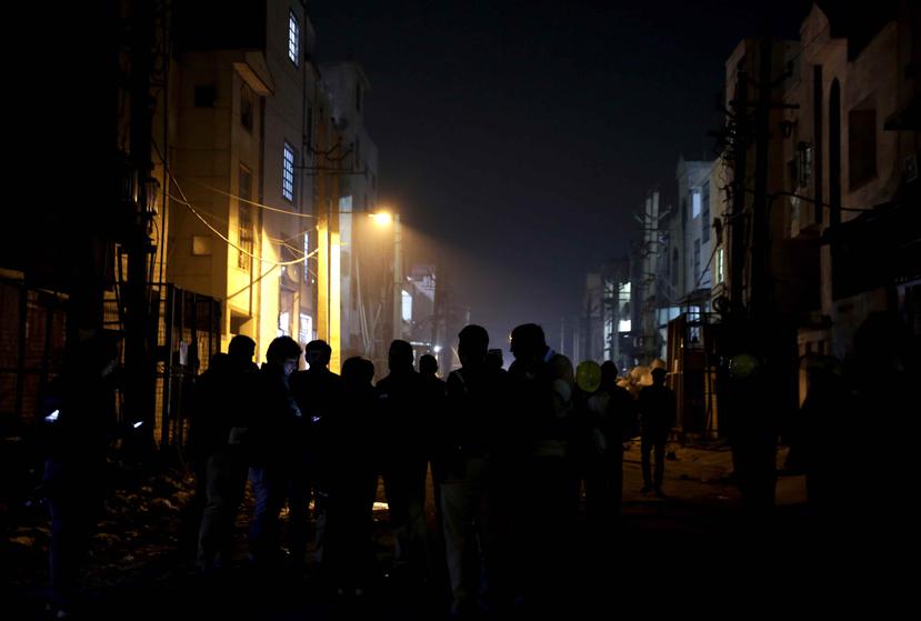 Policías y personal de seguridad montan guardia afuera de una fábrica de petardos que se incendió en las afueras de Nueva Delhi, la India, la madrugada del domingo 21 de enero de 2018. (AP / Altaf Qadri)