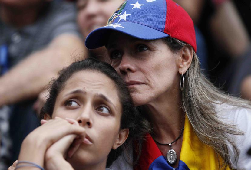 Dos manifestantes antigubernamentales mientras asisten a un acto público en Caracas en honor de los muertos en enfrentamientos entre fuerzas de seguridad y manifestantes. (AP)