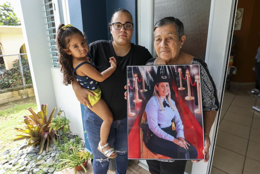 Suleika Bahamonde muestra una foto de su hija, la agente Brenda Pérez Bahamonde. La acompaña la hija de la oficial asesinada, Nicole Colón Pérez, quien carga a su sobrina Lexuanys , de 6 años.