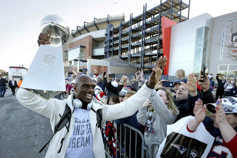 El cornerback de los Patriotas de Nueva Inglaterra Jason McCourty (izquierda) sostiene el trofeo del Super Bowl mientras saluda a aficionados tras la llegada del equipo al Gillette Stadium. (AP)