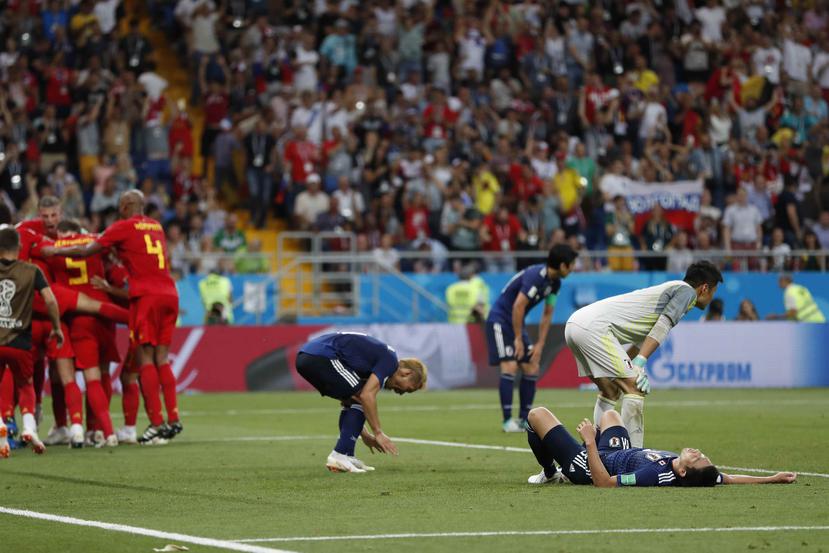 Bélgica celebra el gol de la victoria en el minuto 94 mientras que los jugadores de Japón lamentan la impactante derrota. (AP)