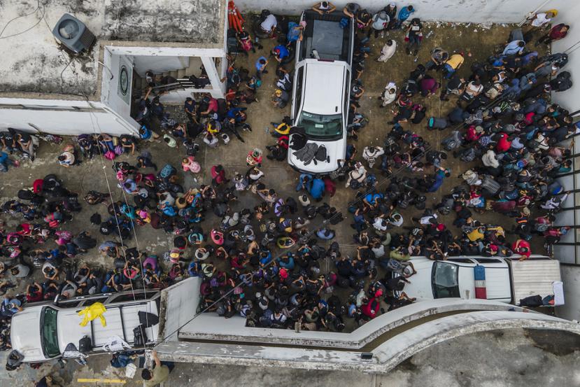 Migrantes se aglomeran en un patio de la procuraduría tras ser interceptados dentro de camiones con remolque.