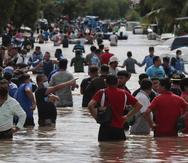 Múltiples personas vadean un camino inundado el jueves 5 de noviembre de 2020 tras el paso del huracán Eta, en Planeta, Honduras.