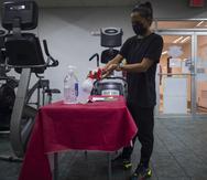 Mientras los gimnasios, salones de belleza, spa y otros comercios se ajustan a las nuevas dispocisiones de la Orden Ejecutiva, muchos de ellos continúan con sus protocolos de higiene para prevenir la propagación del virus de COVID-19. En la foto, Clarisa Cruz, encargada de piso del gimnasio Fit Muscle en Guaynabo.