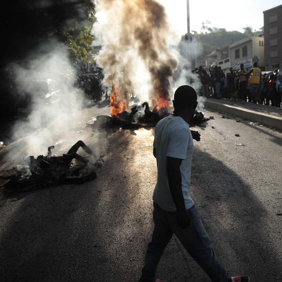 Un grupo de personas observa los cadáveres de presuntos pandilleros que fueron quemados vivos por una turba en la sección Canape Vert de Puerto Príncipe, Haití, el lunes 24 de abril de 2023. (AP Foto/Odelyn Joseph)