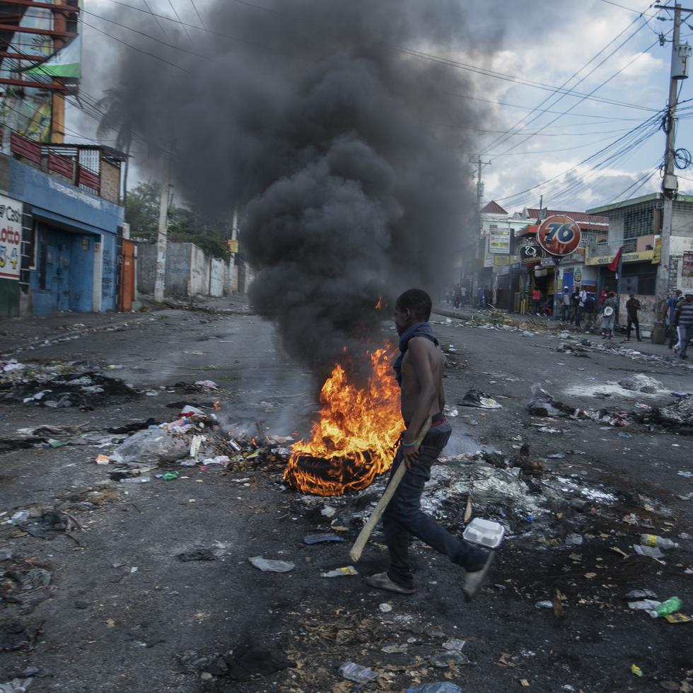 A man walks past burning tires set up by protesters during a protest demanding the resignation of Prime Minister Ariel Henry in the Delmas area of Port-au-Prince, Haiti, Monday, Oct. 10, 2022. (AP Photo/Odelyn Joseph)