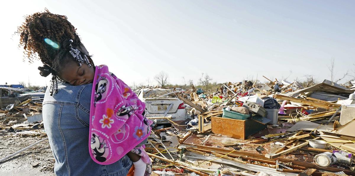 Wonder Bolden acuna a su nieta de un año, Journey Bolden, mientras observa los restos de la casa móvil de su madre demolida por el tornado en Rolling Fork, Mississippi.