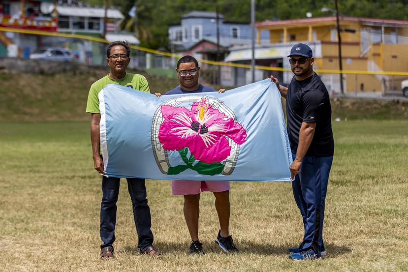 Alvin Santiago Negrón, Jesse Irizarry Mercado y Gilbert González Rodríguez muestran orgullosos la bandera del barrio Magas Abajo, en Guayanilla.