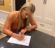 Laura Stockton, hija del miembro del Salón de la Fama John Stockton, firmando su contrato que le permitirá jugar en Puerto Rico con las Montañeras de Morovis.