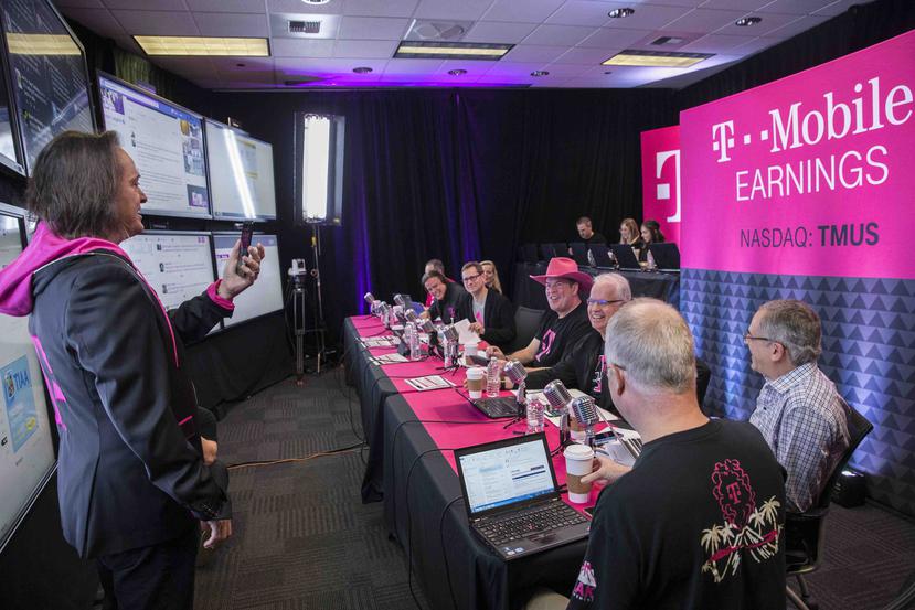 John Legere (i), presidente y principal oficial ejecutivo de T-Mobile, transmite desde su teléfono celular durante una conferencia celebrada hoy. (AP)