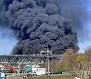 En esta foto provista por la policía estatal de Connecticut, gruesas columnas de humo se alzan de un incendio provocado por el choque entre un camión cisterna de combustibles y un auto en el puente  Gold Star Memorial en Groton,  Connecticut, viernes 21 de abril de 2023.