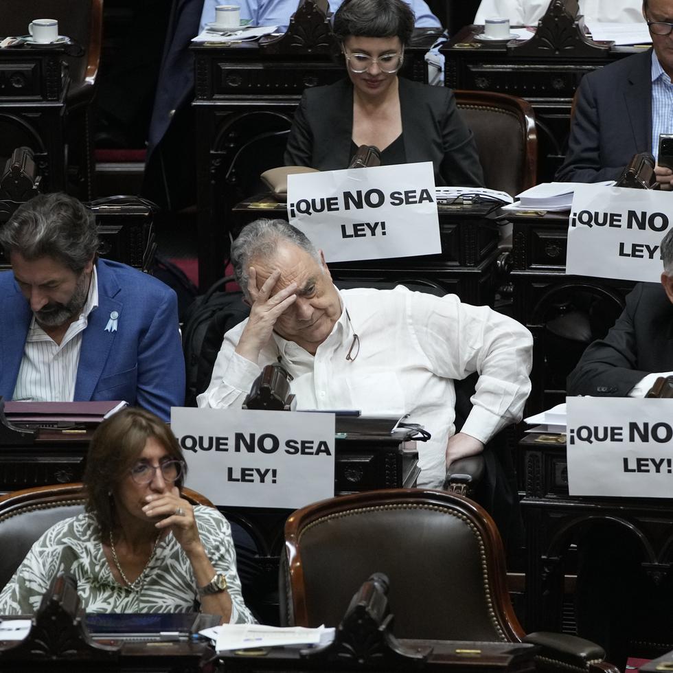 Legisladores en el debate de la reforma económica del presidente argentino Javier Milei en la Cámara de Diputados con carteles de rechazo para que no sea aprobada.