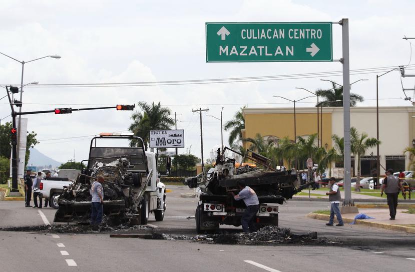 Vehículos quemados son retirados de la vía pública tras registrase una emboscada a un convoy del Ejército mexicano. (EFE / Noroeste)