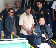 Foto de 2009 en la que se ve a Joseph González (atrás), actual director del FBI en Puerto Rico, que en aquel momento era el agente a cargo de la investigación contra Ángel Ayala Vázquez, mejor conocido como Ángelo Millones (al centro, esposado).