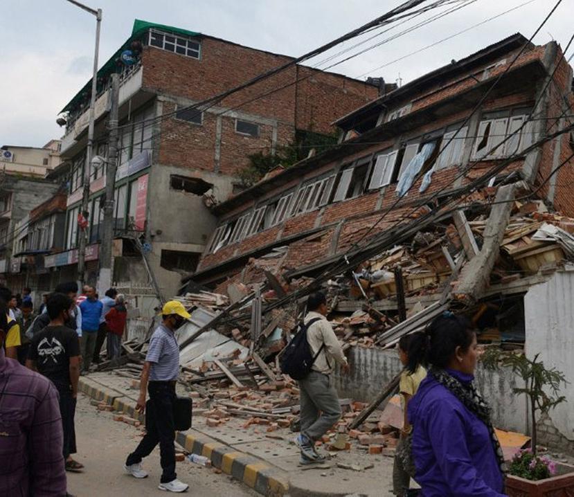 La gente camina frente a edificios colapsados por el fuerte temblor. (AFP)