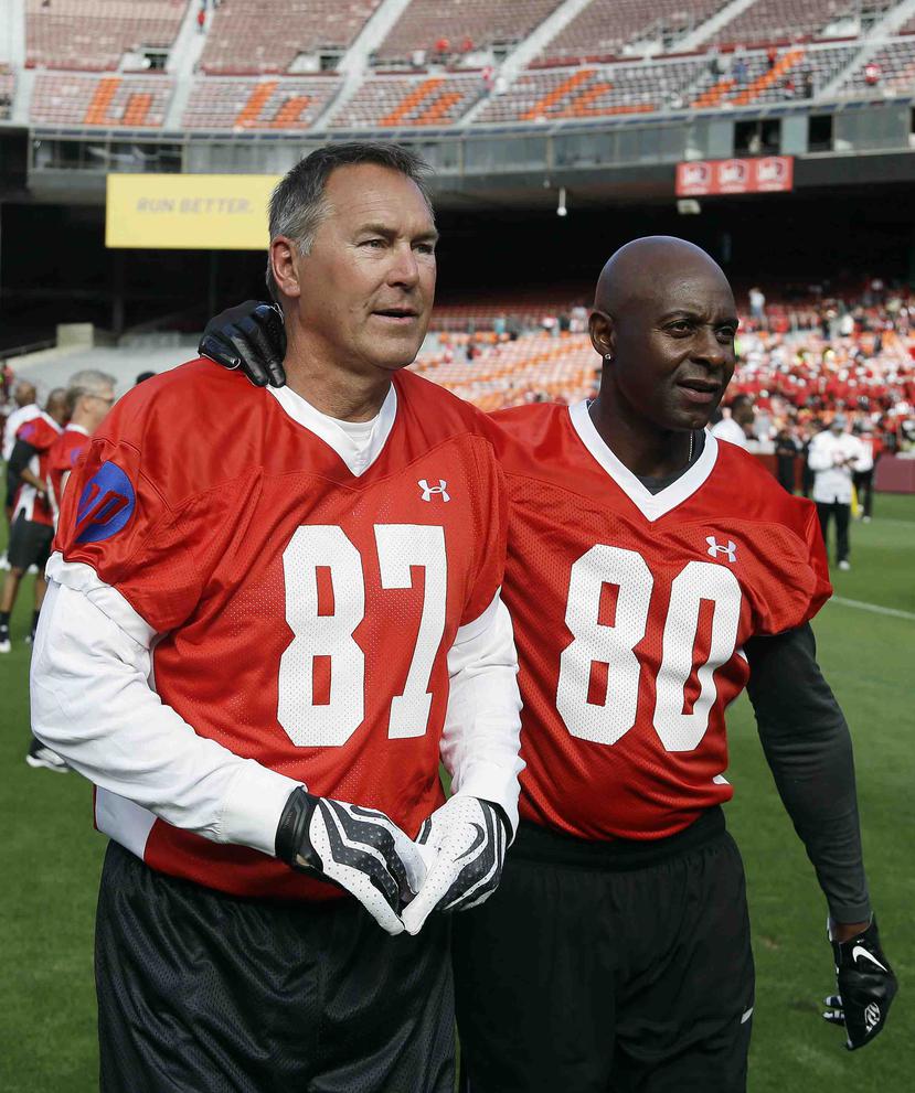 Dwight Clark, a la izquierda, camina junto a Jerry Rice por el campo de fútbol en un juego celebrado en San Francisco. (AP)