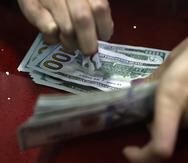 Fotografía de archivo que muestra a una persona contando billetes de cien dólares.