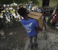 Un hombre carga dos cajas que contienen alimentos el miércoles 18 de agosto de 2021, en Les Cayes, Haití, las cuales fueron enviadas por el gobierno de la ciudad para los residentes que se quedaron sin hogar luego del sismo de magnitud de 7.2 que sacudió la nación.