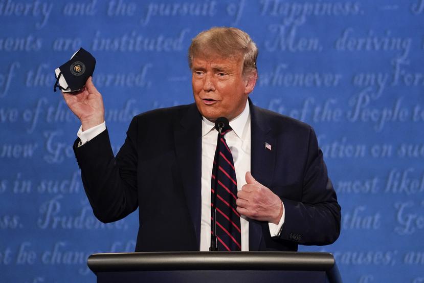 El presidente Donald Trump levanta una mascarilla durante el primer debate presidencial frente a Joe Biden.