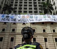 Un guardia de seguridad de pie ante una pancarta que dice "Sanen al mundo, luchamos como uno", en Filipinas. (AP)