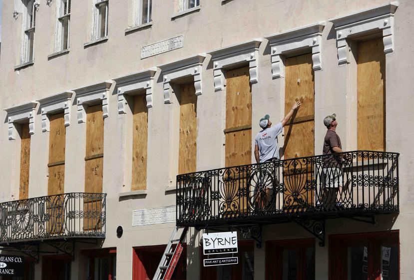 Dos personas colocan paneles de madera en Confederate House en el centro de la ciudad de Charleston, en Carolina del Sur. (AP)