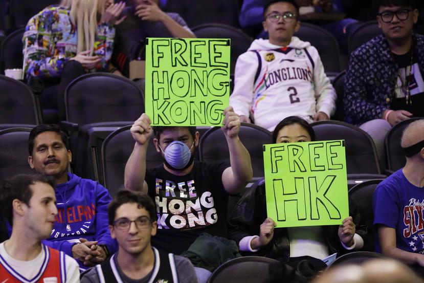 Fanáticos sostienen letreros pidiendo la liberación de Hong Kong de China durante un partido de pretemporada entre los 76ers de Filadelfia y los Loong-Lions de Guangzhou. (AP Photo/Matt Rourke)