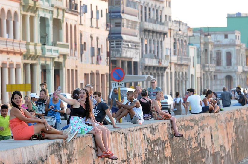Cubanos y turistas conversan sentados en una zona del malecón, en La Habana (Cuba). (EFE/Ernesto Mastrascusa)